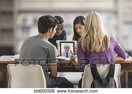 Stock Photo - Friends studying together using digital tablet. Fotosearch