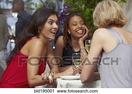 Stock Image - Friends talking over dinner in restaurant. Fotosearch