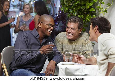 Stock Photo - Friends talking over dinner in restaurant. Fotosearch