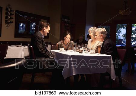 Stock Photo - Friends watching woman blow out birthday cupcake in restaurant. Fotosearch