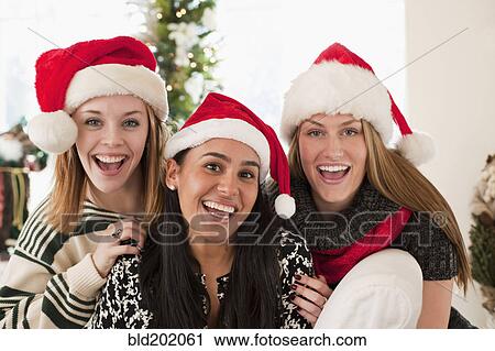 Stock Image - Friends wearing Santa hats. Fotosearch