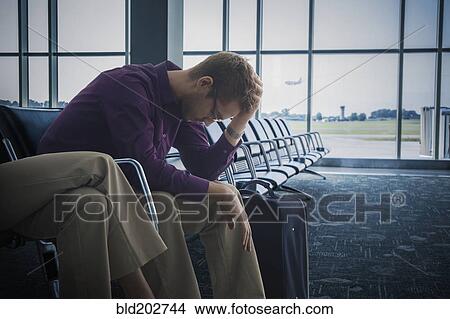 Picture - Frustrated Caucasian man sitting airport. Fotosearch