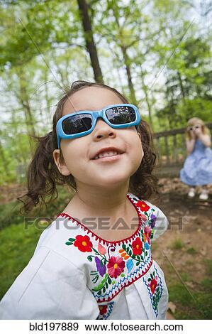 Stock Photo - Girl in sunglasses standing outdoors. Fotosearch