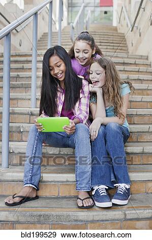 Stock Photo - Girls using digital tablet on staircase. Fotosearch