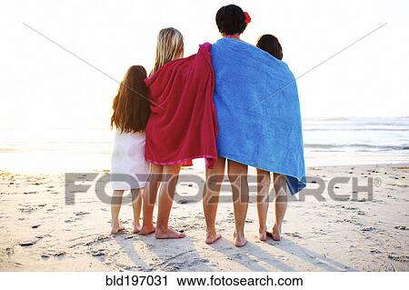 Stock Image - Girls wrapped in towels standing on beach. Fotosearch