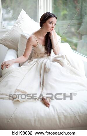 Stock Image - Glamorous Caucasian woman sitting on sofa. Fotosearch
