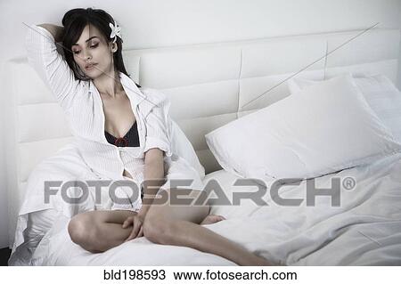 Stock Image - Glamorous woman reclining in bed. Fotosearch