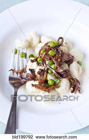 Stock Image - Gnocchi and peas in bowl with fork. Fotosearch