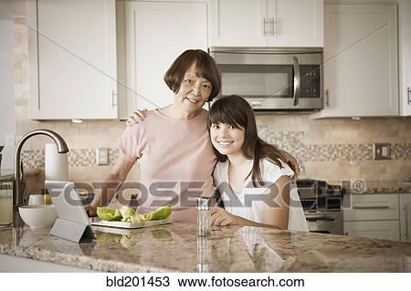 Stock Image - Grandmother and granddaughter preparing food. Fotosearch