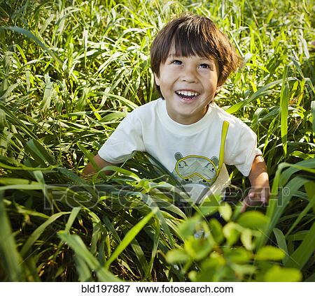 Grinning mixed race boy sitting in long grass View Large Photo Image Stock Photo - Grinning mixed race boy sitting in long grass. Fotosearch