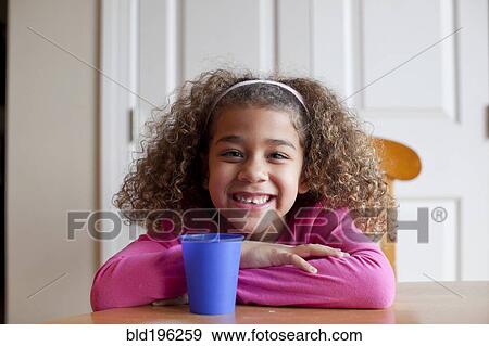 Stock Photo - Grinning mixed race girl sitting with cup. Fotosearch