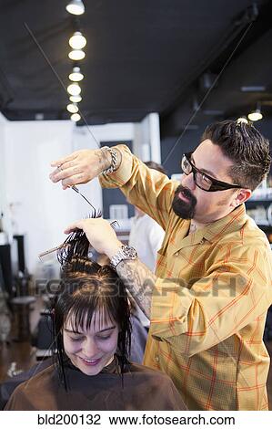 Stock Image - Hairdresser cutting hair in salon. Fotosearch