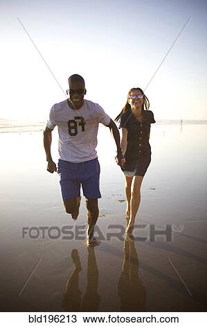 Happy couple holding hands and running on beach View Large Photo Image Stock Image - Happy couple holding hands and running on beach. Fotosearch