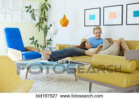 Happy couple relaxing on sofa with digital tablet View Large Photo Image Stock Photo - Happy couple relaxing on sofa with digital tablet. Fotosearch