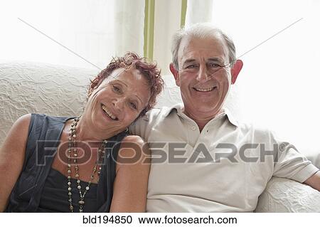 Stock Image - Happy couple sitting on sofa. Fotosearch