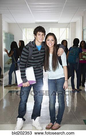 Stock Image - High school friends standing in corridor together. Fotosearch