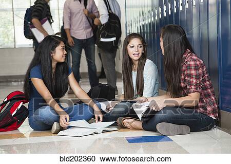 Stock Image - High school students sitting in corridor together. Fotosearch