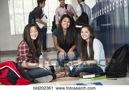 Stock Image - High school students sitting in corridor together. Fotosearch