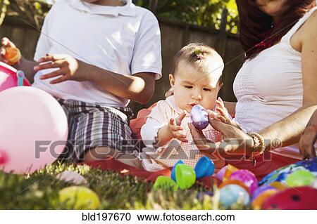 Stock Image - Hispanic baby playing with Easter eggs. Fotosearch