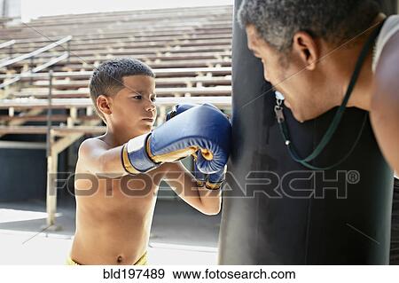 Stock Photo - Hispanic boy boxing punching bag. Fotosearch