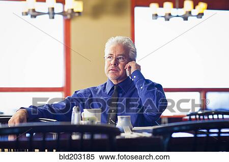 Stock Photography - Hispanic cafe owner talking on cell phone. Fotosearch
