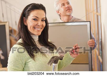 Picture - Hispanic couple decorating home together. Fotosearch