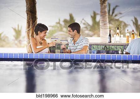 Hispanic couple drinking cocktails at poolside View Large Photo Image Stock Photograph - Hispanic couple drinking cocktails at poolside. Fotosearch
