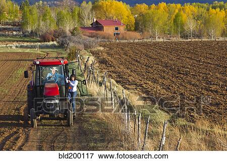 Stock Photo - Hispanic couple driving tractor on farm. Fotosearch