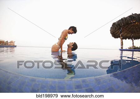 Stock Photo - Hispanic couple enjoying swimming pool. Fotosearch