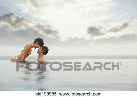 Stock Photography - Hispanic couple enjoying swimming pool. Fotosearch