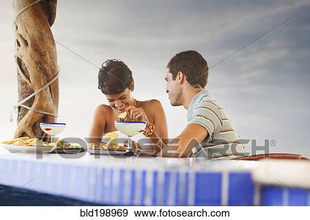 Hispanic couple having dinner at poolside View Large Photo Image Stock Photo - Hispanic couple having dinner at poolside. Fotosearch