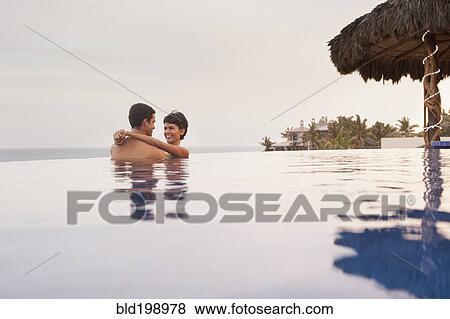 Stock Photo - Hispanic couple hugging in swimming pool. Fotosearch
