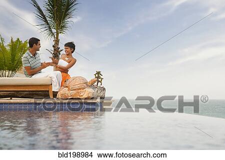 Picture - Hispanic couple relaxing near swimming pool. Fotosearch