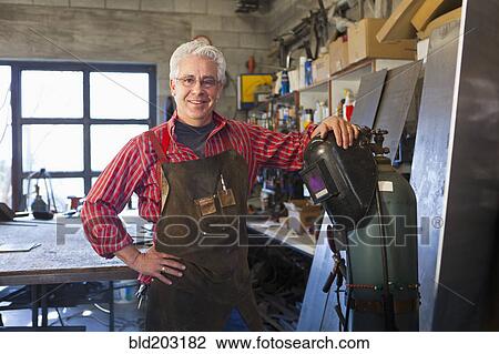 Stock Image - Hispanic craftsman working in shop. Fotosearch