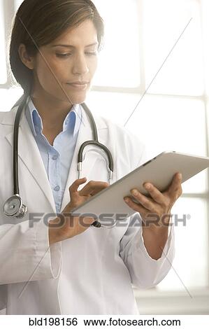 Stock Photograph - Hispanic doctor using digital tablet. Fotosearch