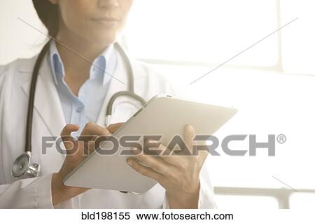 Hispanic doctor using digital tablet View Large Photo Image Stock Photography - Hispanic doctor using digital tablet. Fotosearch