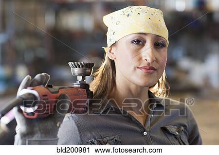Stock Image - Hispanic factory worker holding metal fabricator. Fotosearch
