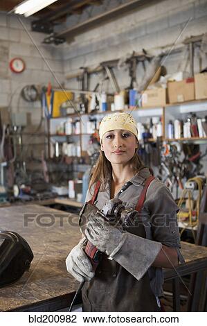 Stock Image - Hispanic factory worker holding metal fabricator. Fotosearch