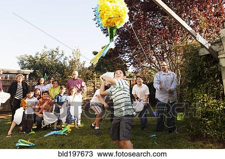 Stock Image - Hispanic family breaking pinata in backyard. Fotosearch