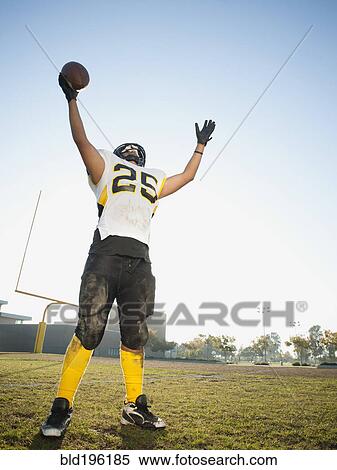 Stock Photography - Hispanic football player cheering on football field. Fotosearch