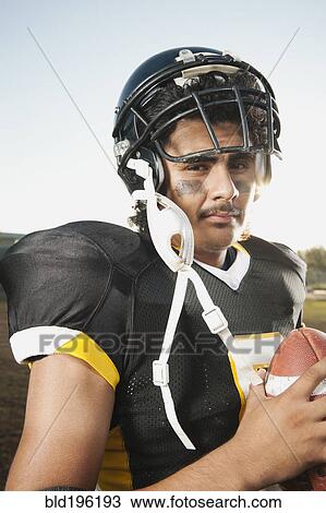 Stock Image - Hispanic football player holding football. Fotosearch