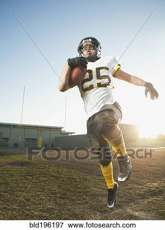 Stock Photo - Hispanic football player running with football. Fotosearch