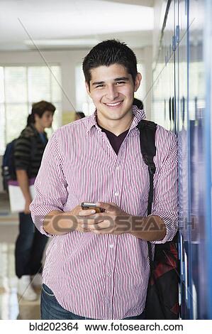 Picture - Hispanic high school student holding cell phone. Fotosearch