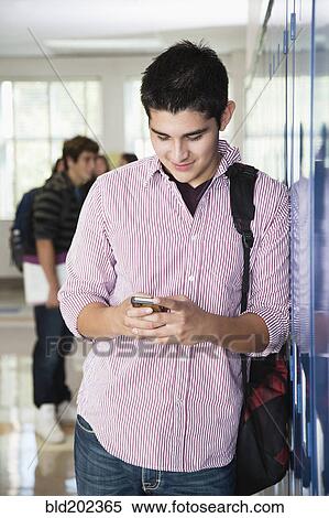 Stock Photography - Hispanic high school student text messaging on cell phone. Fotosearch