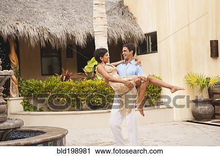 Hispanic man carrying wife in courtyard View Large Photo Image Stock Image - Hispanic man carrying wife in courtyard. Fotosearch