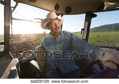 Stock Image - Hispanic man driving tractor. Fotosearch