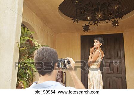 Picture - Hispanic man taking photograph of wife. Fotosearch