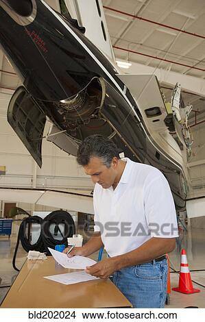 Picture - Hispanic man working in airplane hangar. Fotosearch