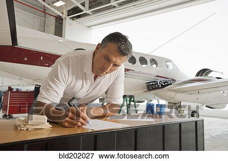Hispanic man working in airplane hangar View Large Photo Image Stock Photo - Hispanic man working in airplane hangar. Fotosearch