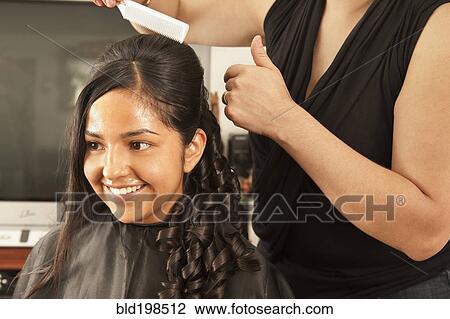 Stock Image - Hispanic woman having hair styled in salon. Fotosearch